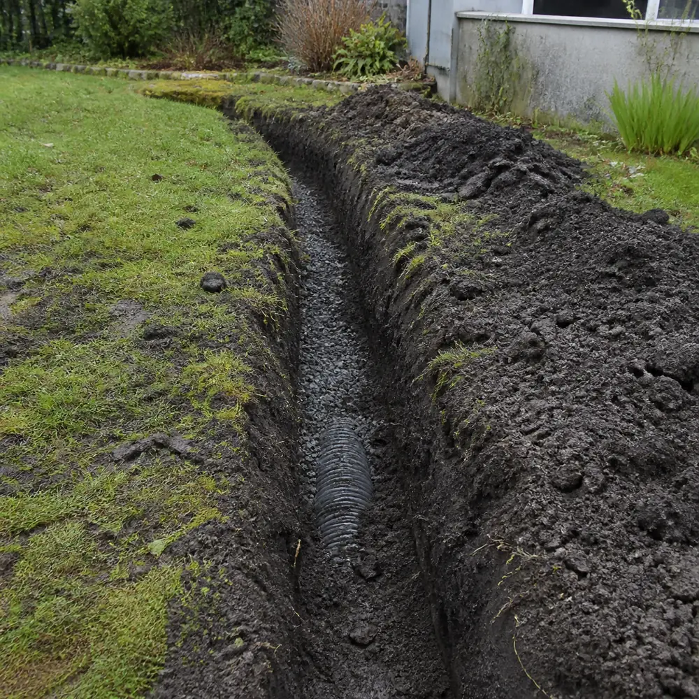 Tranchée ouverte dans un jardin pour des travaux de mise en conformité d'un système d'assainissement individuel