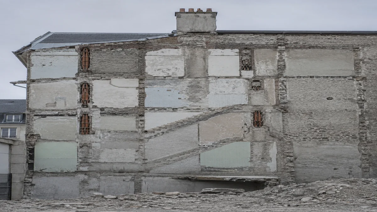 Mur mitoyen ancien mis à nu après démolition, montrant les arrachements de plancher et les traces d'anciens conduits