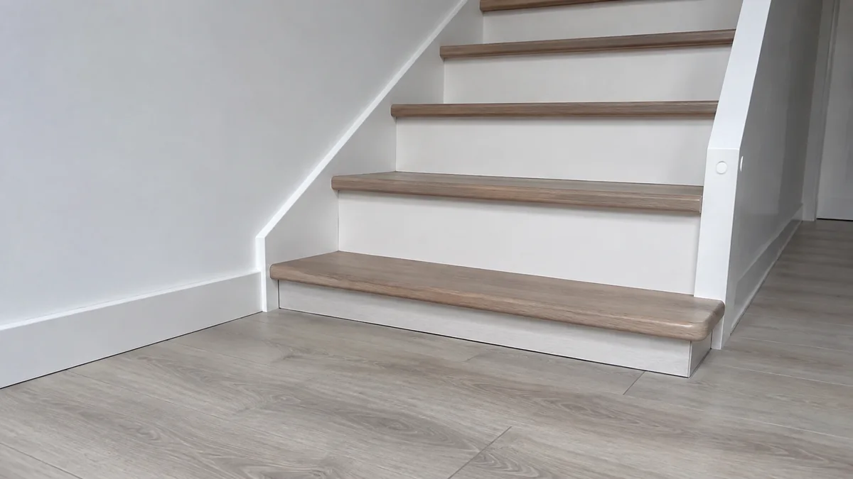 Bas d'une volée d'escalier dont la première contremarche est réduite par le revêtement de sol rapporté