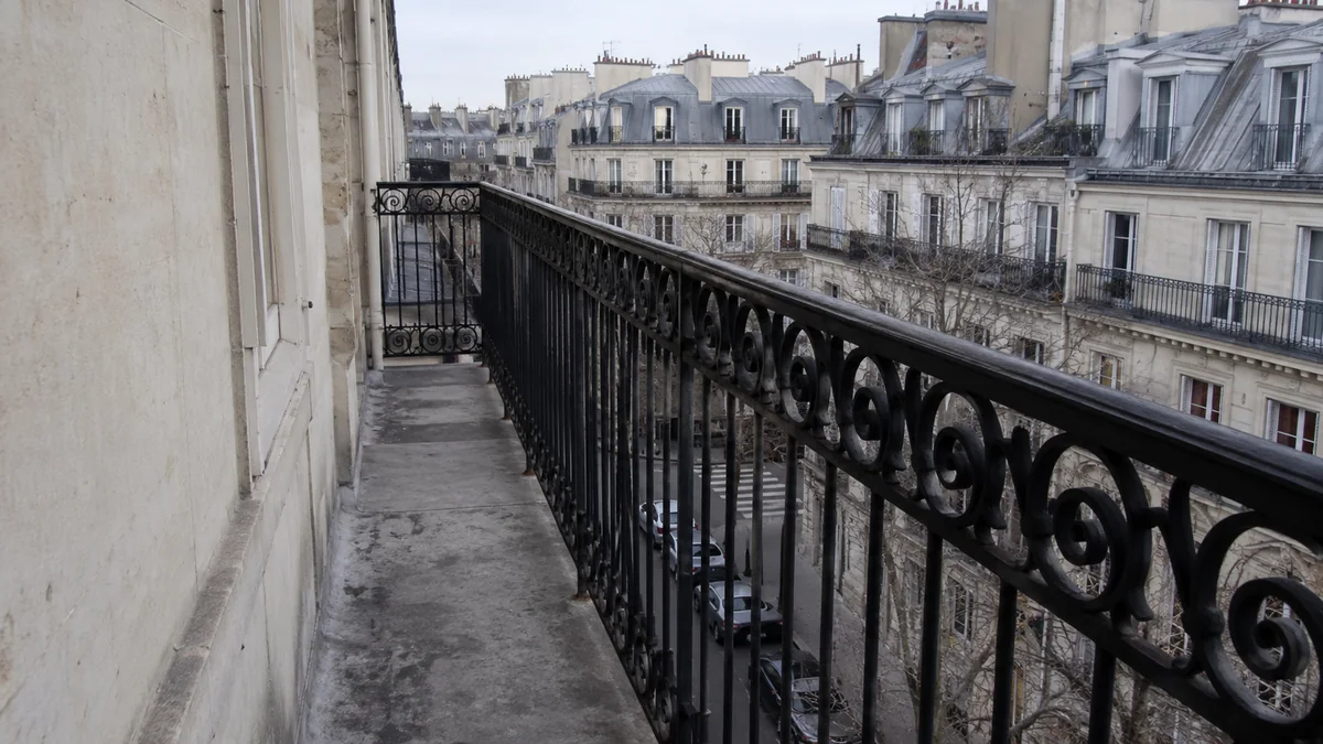 Balcon parisien bordé de son garde-corps en fer forgé d'origine, vu depuis le balcon