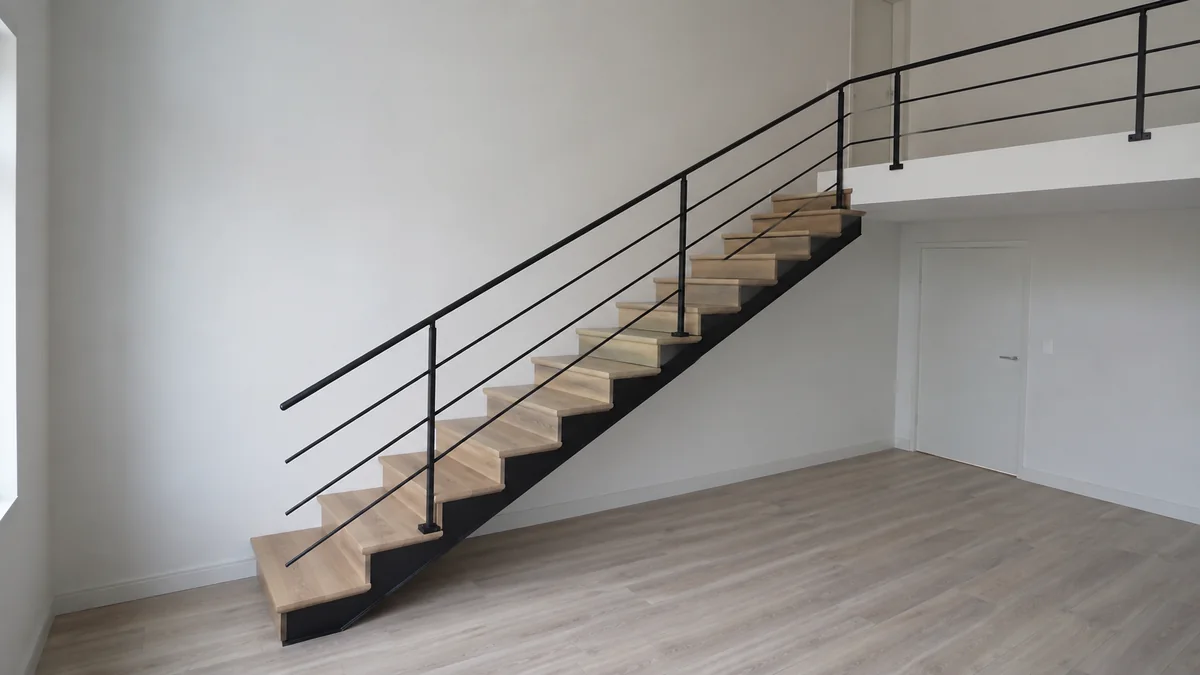 Escalier droit vu de côté, bordé d'un garde-corps métallique à lisses horizontales trop bas