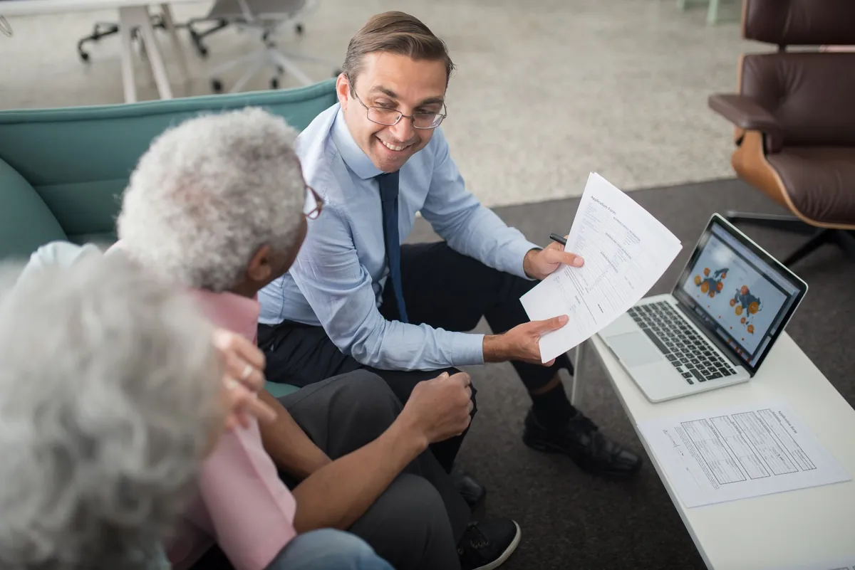 Conseiller échangeant avec des clients autour de documents d'assurance, saisine du médiateur des assurances