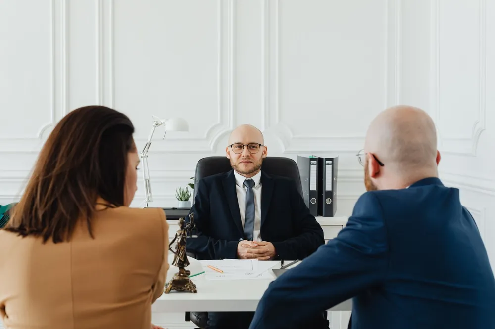 Avocat en consultation avec des clients dans un bureau, échange autour d'un dossier de litige de construction